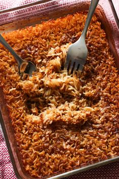 a casserole dish filled with rice and two forks