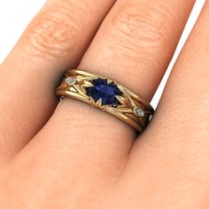 a woman's hand wearing a gold ring with a blue sapphire stone in the center