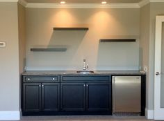 an empty kitchen with black cabinets and stainless steel appliances