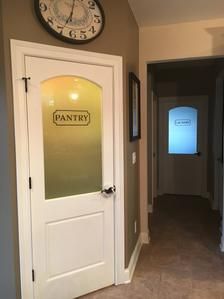 an empty hallway with a clock on the wall and a sign that says pantry next to it