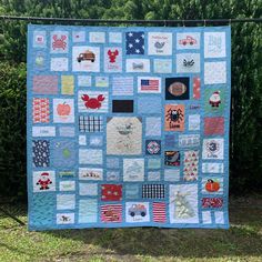 a quilted wall hanging in front of some bushes and trees with patches on it