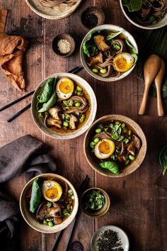 three bowls filled with soup and vegetables on top of a wooden table next to spoons