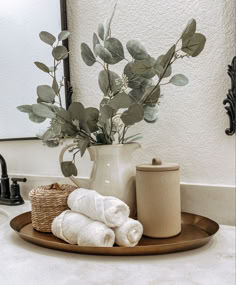 a bathroom sink with towels and a vase on it