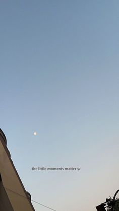 the moon is seen in the sky above a building with a clock on it's side