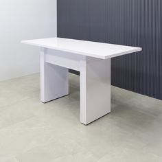 a white table sitting on top of a tiled floor next to a black and white wall