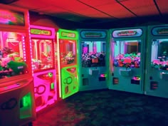 several vending machines are lit up with neon lights and flowers in the center, along with other vending machines