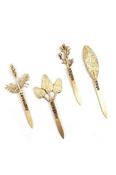 three golden spoons and two gold flower brooches with words on them are shown