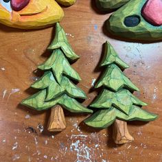 two wooden christmas trees on a table next to some other wood toys and paper machs