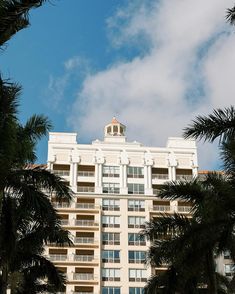 an apartment building with palm trees surrounding it and a clock tower on the top floor