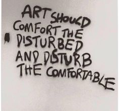 the words art should comfort the disturbed and disturb the comfortable are spray painted on a wall