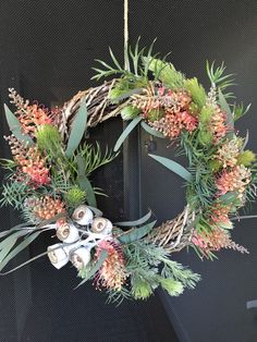 a wreath with flowers and candles hanging on a wall