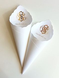 two white paper cones with gold monogrammed initials on them, one is folded in half