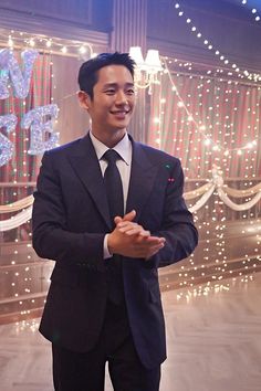 a man wearing a suit and tie standing in front of christmas lights