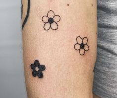 a woman's arm with three small flowers on it, and one is black