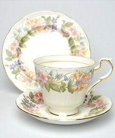 an antique tea cup and saucer with flowers on the rim, sitting side by side