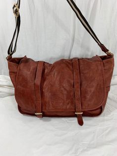 "Measurements are 17\" wide, 11\"5 high, 8\" deep with one 44\" shoulder strap with a 18\" drop. On the interior there is one large main compartment, back zipper pocket, cell phone slot and two front buckle closures. Bag is made of pebbled leather with silver/gold tone hardware, strong leather with no tears and bag was well cared for. The color of this bag is between currant red and light brown. This leather messenger bag is spacious with great detail and bag can be used crossbody. ------------- Crossbody School Travel Bag, School Crossbody Travel Bag, Satchel Hobo Bag With Detachable Strap For School, Classic Burgundy Shoulder Bag For Travel, School Satchel Hobo Bag With Detachable Strap, Burgundy Shoulder Bag For Travel, School Satchel Travel Bag With Adjustable Strap, Burgundy Leather-lined Travel Bag, Leather Satchel With Adjustable Strap