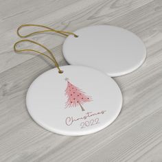 two white ceramic ornaments with a pink christmas tree on them