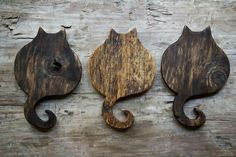 three wooden cats are hanging on the wall