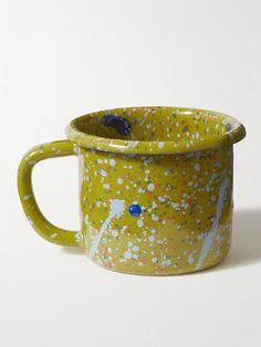 a yellow cup with blue and white speckles on it's rim, sitting on a white surface