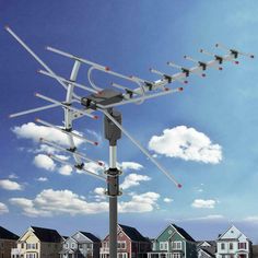 an antenna on top of a pole in front of some houses and blue sky with white clouds