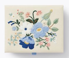 a white wall hanging with blue and pink flowers on it