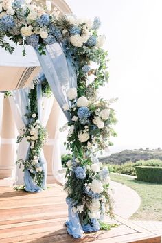 a blue and white wedding arch decorated with flowers