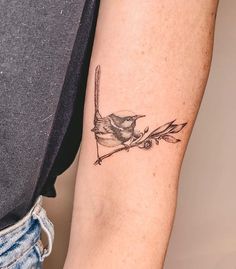 a small bird on a branch tattoo on the arm