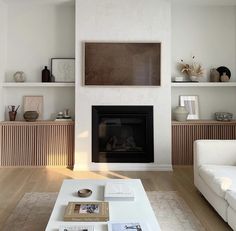 a living room with white furniture and a fireplace