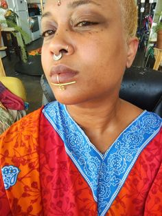 a woman with piercings on her nose sitting in a chair