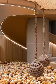 two balls hanging from ropes in a room filled with rocks and pebbles on the floor