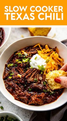 slow cooker texas chili in a bowl with tortilla chips and sour cream