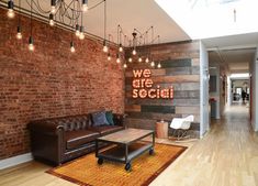 a living room with brick walls and wooden flooring that says we are social on the wall