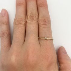 a person's hand with a gold ring on top of their finger and a diamond in the middle