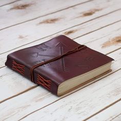 a brown leather bound book sitting on top of a wooden table