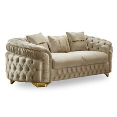 a beige couch with gold trimmings and pillows on the armrest, sitting in front of a white background