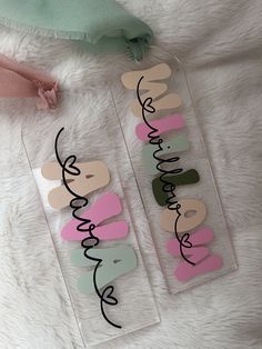 two clear plastic tags with the words happy birthday written in black ink on them next to a pink and green teddy bear