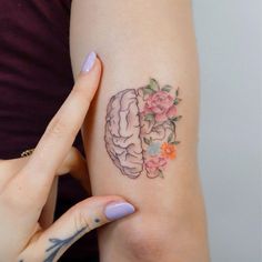 a woman's left arm with a flowered tattoo on the side of her right arm