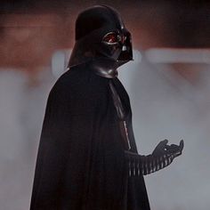 darth vader standing in the fog with his hand on his hip and looking at something