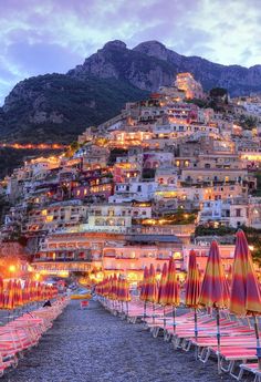 an image of a beach with umbrellas and buildings on the hill in the background