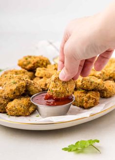 a person dipping sauce onto some food on a plate