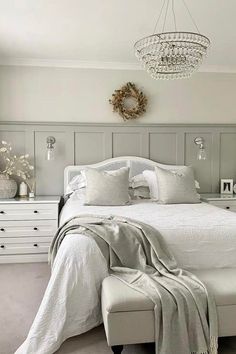 a white bed sitting under a chandelier in a bedroom