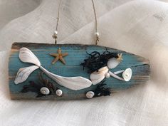 a wooden sign with sea shells and starfishs hanging from it's sides