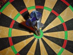 an overhead view of a dart hitting in the center of a bullseye darts target