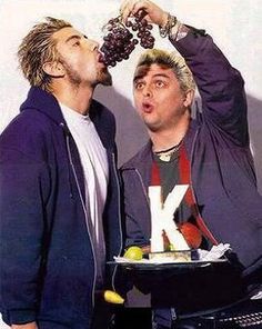 two men are eating grapes from a platter