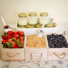 three wooden trays filled with fruit and granola on top of a white table