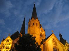 an old church with steeples lit up at night