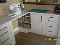 a sewing machine sitting on top of a white counter next to drawers and baskets in front of a mirror