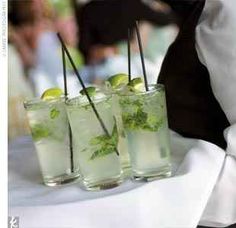 three glasses filled with drinks sitting on top of a white table cloth covered tablecloth