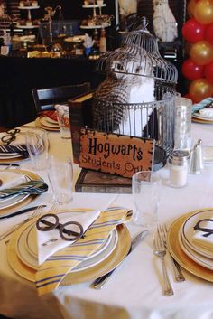 a table set with plates, silverware and a birdcage for harry potter