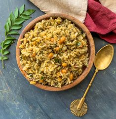 a wooden bowl filled with rice and carrots next to a spoon on top of a table